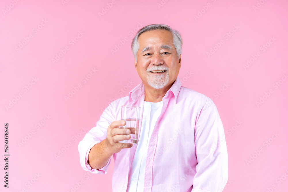 happy asian old man hand holding glass of water drinking smile wearing pink shirt and pink black background. happy asian old man hand holding glass of water drinking smile wearing pink shirt and pink black background.