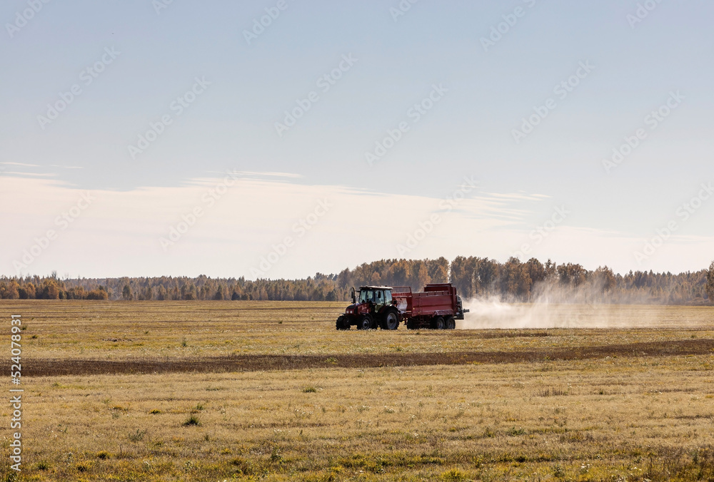 Fototapeta premium tractor spreads chemical fertilizer on the field in autumn