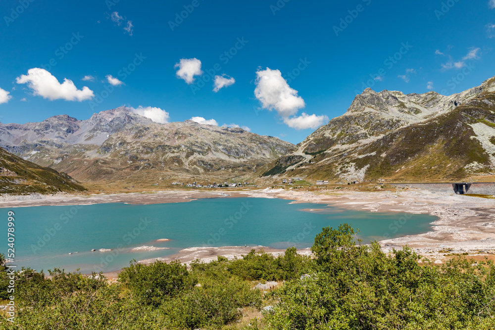 Panoramic view of Montespluga lake on a sunny summer day. The lake is nearly empty due to climate change. Spluga Pass