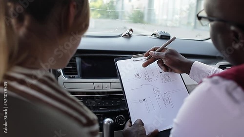 Driving school concept video. A car instructor teaches a young woman how to drive. Teaching the rules of the road and driving a vehicle