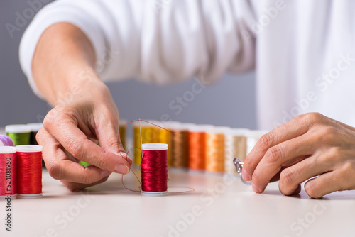 red chilo hands with a needle, dressmaker, atelier, sewing, sewing clothes, embroidering a fabric, selective focus photo