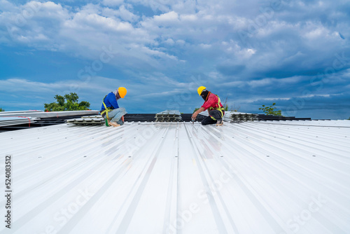 Teamwork of Roofer working at new roof under construction. Safety body construction, Fall arrestor device for worker with hooks for safety body harness on the roof structure. building photo