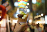 Hand holding a Japanese Matcha latte soft serve ice cream with red bean and waffle biscuit