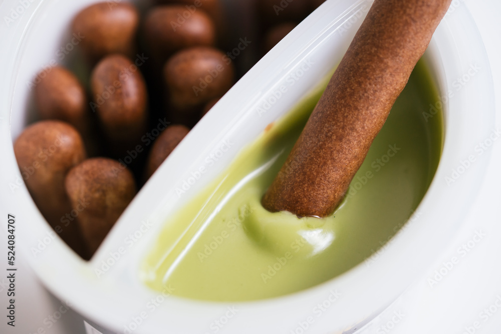 Close up of the chocolate biscuit stick dipping the green tea cream sauce Close up of the chocolate biscuit stick dipping the green tea cream sauce