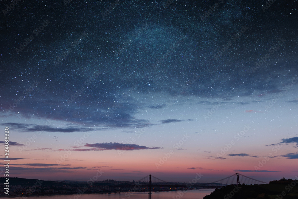 Beautiful vintage city of Lisbon with river, bridge and colorful sunset  evening sky with stars. Amazing starry sky. Space wallpaper Stock Photo