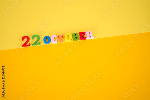 22 October on a yellow, paper background with wooden and multicolored letters. photo