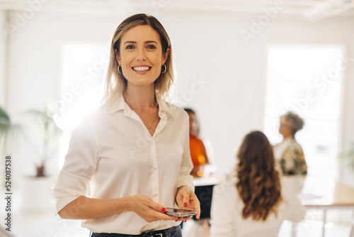 Cheerful young businesswoman holding a smartphone in a meeting room photo