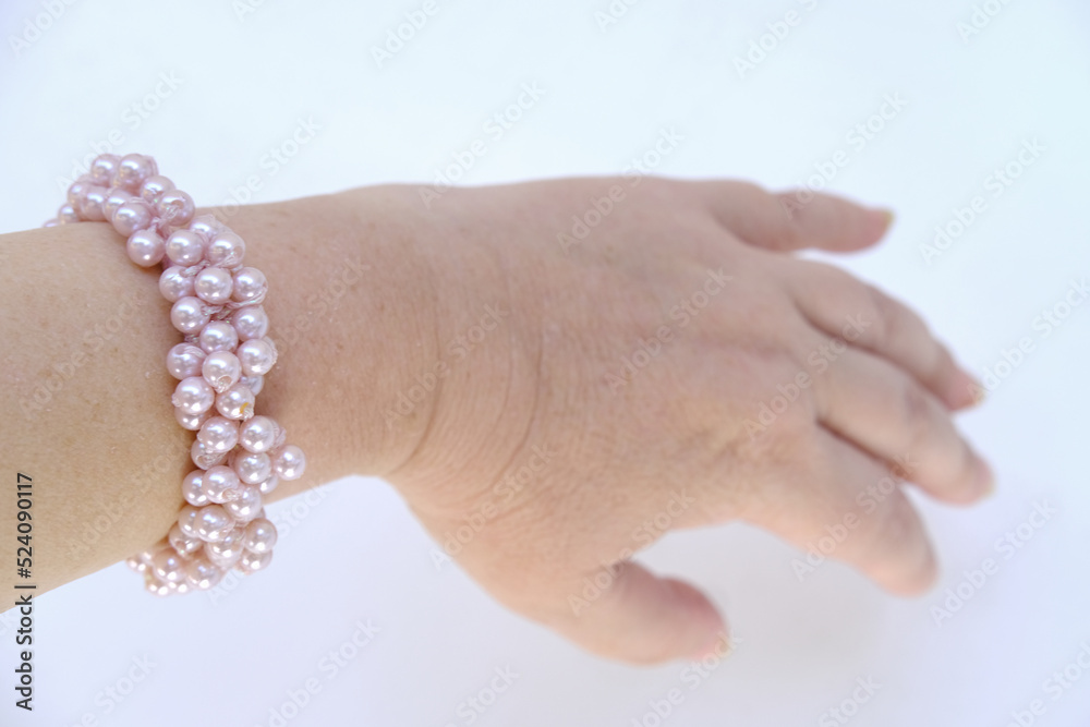 beautiful bracelet made of pink pearls, elastic band, scrunchie on female hand on a white background close-up, the concept of women's accessories and jewelry, easy to do hairstyle, everyday hair item