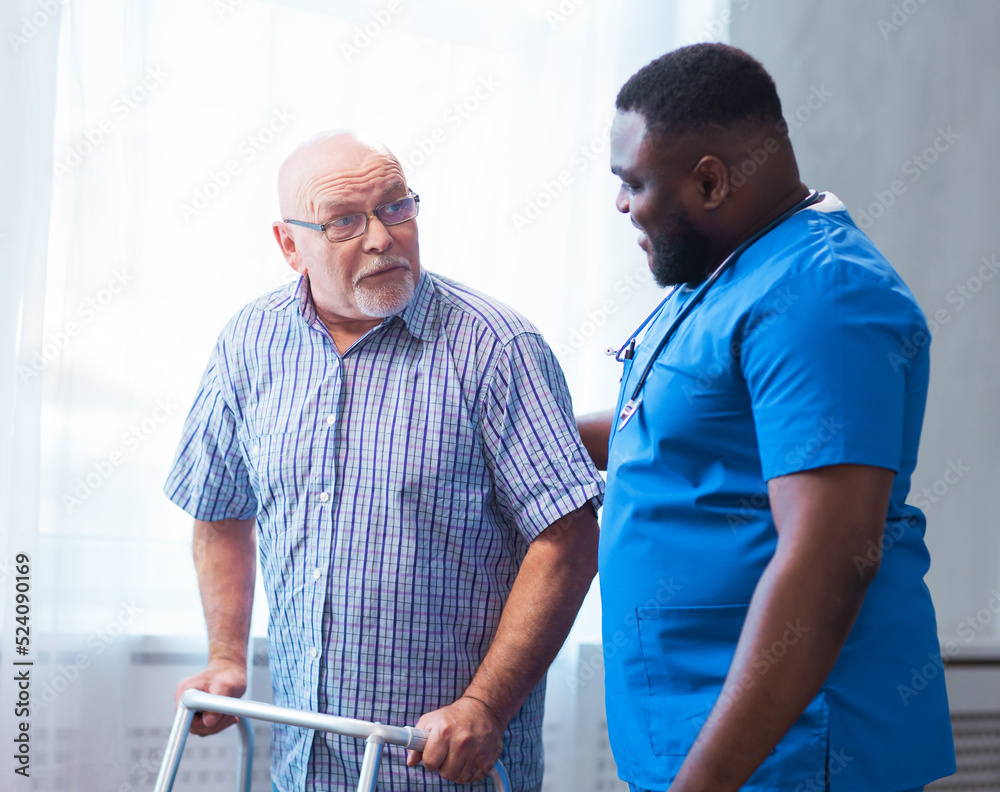 Fototapeta premium Professional doctor helps an elderly man with chronic diseases. Therapist and patient in home interior. Health care and medicine concept.