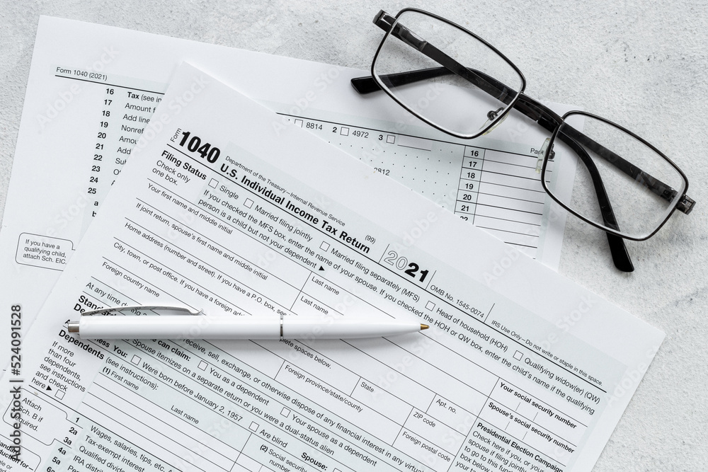 US individual tax form with pen and glasses on businessman table US individual tax form with pen and glasses on businessman table