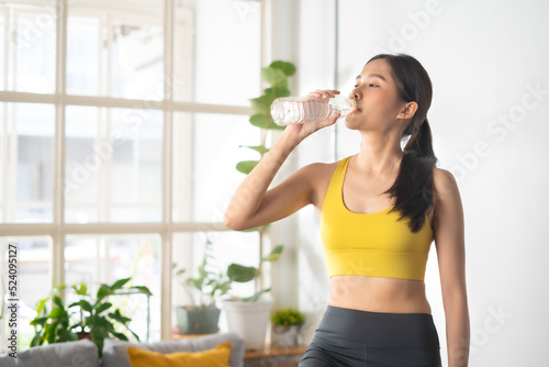 Beautiful Asian woman in sportwear take break cool down and drinking water after exercise cardio training workout at home gym