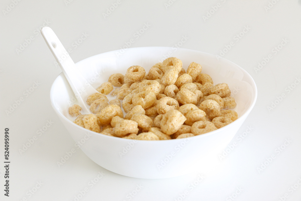 Healthy morning oat cereal, cheerios in bowl of milk with spoon, low sugar and high fibre breakfast, isolated on white background Healthy morning oat cereal, cheerios in bowl of milk with spoon, low sugar and high fibre breakfast, isolated on white background