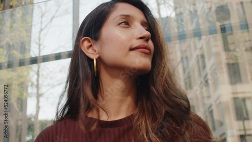Young smiling businesswoman standing on street in front of glass wall