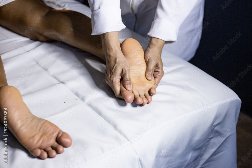 Detalhe das mãos de massagista aplicando massagem terapêutica no pé de um  paciente que está deitado em uma maca com lençol branco. Stock Photo |  Adobe Stock