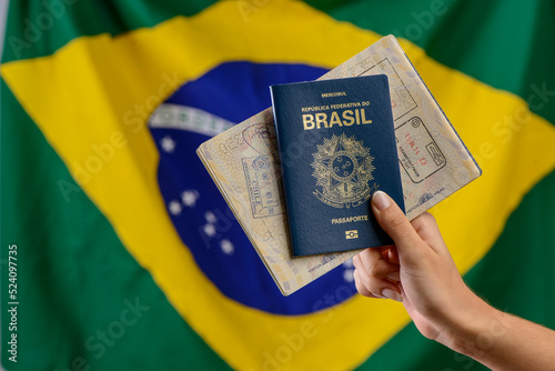 Cuadro en lienzo Hand holding Brazilian passport with Brazilian flag in the blurred background