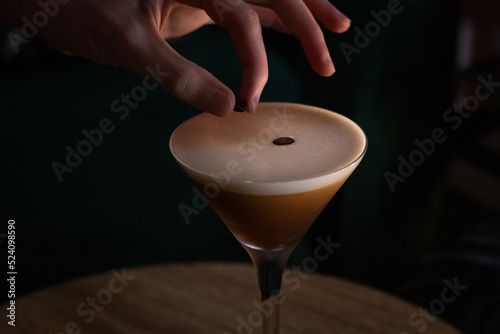 espresso martini cocktail with foam and three coffee beans with hand 