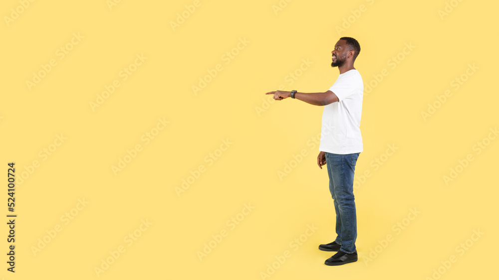 African Man Pointing Finger Aside At Empty Space, Yellow Background African Man Pointing Finger Aside At Empty Space, Yellow Background