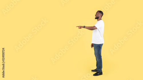 African Man Pointing Finger Aside At Empty Space, Yellow Background