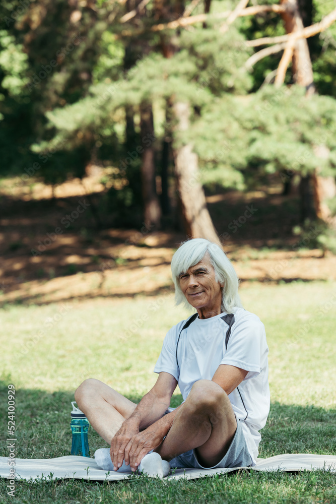 cheerful senior man with grey hair sitting in white socks on fitness mat. cheerful senior man with grey hair sitting in white socks on fitness mat.