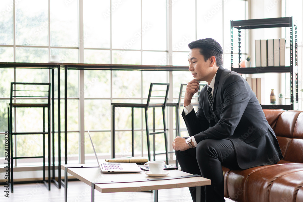 Asian businessman executive manager looking at a laptop computer, thinking about stock and crypto market volatility or meeting an online webinar and waiting for the decision in the office. Asian businessman executive manager looking at a laptop computer, thinking about stock and crypto market volatility or meeting an online webinar and waiting for the decision in the office.