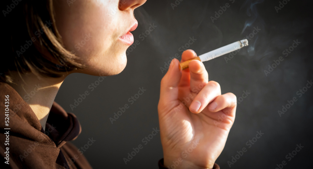 Fototapeta premium Woman is smoking, holding a cigarette in her hand.