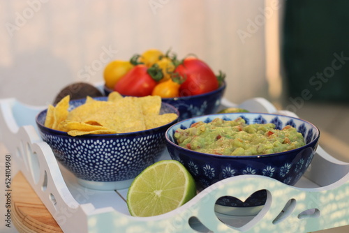 Guacamole home made with tortilla chips ripe red and yellow tomatoes and lime served photo