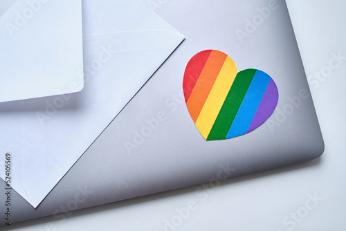 Rainbow heart pasted on laptop and white envelope. LGBT flag. LGBTQIA Pride Month in June. Lesbian gay bisexual transgender. Gender equality. Human rights and tolerance. Rainbow flag