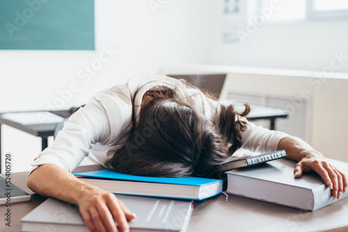 Tired female student sleeping on desk face and hands on books