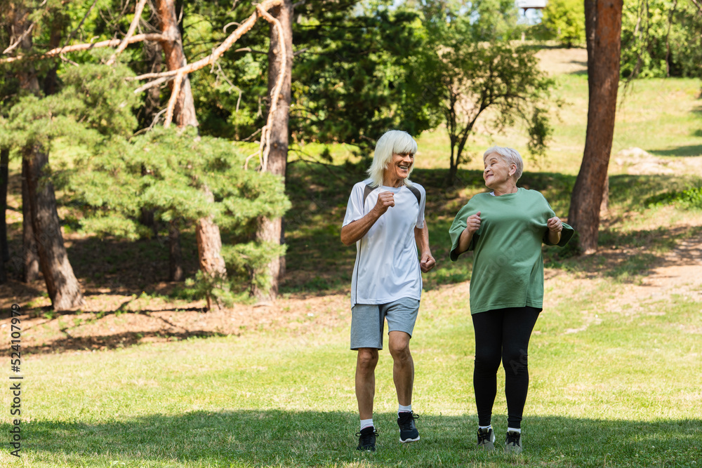 full length of senior couple in sportswear running in green park. full length of senior couple in sportswear running in green park.