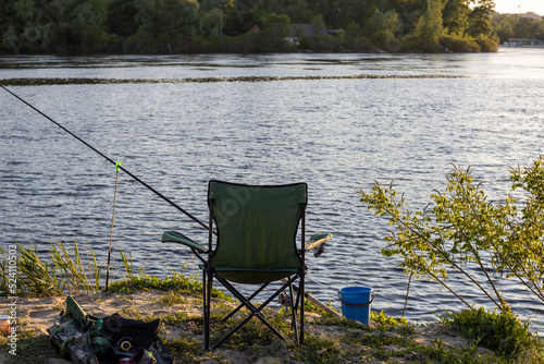 Landscape with a fisherman's chair and fishing rods on the lake shore, fishing as a hobby, early spring in nature