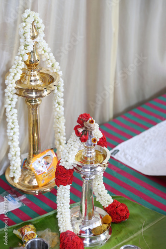 two brass and silver lamps are decorated with jasmine flower garlands in a religious function