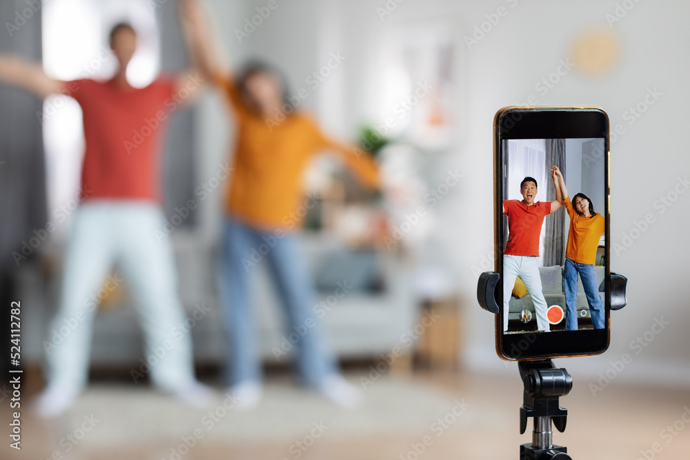 Funny asian husband and wife recording video, using smartphone Funny asian husband and wife recording video, using smartphone