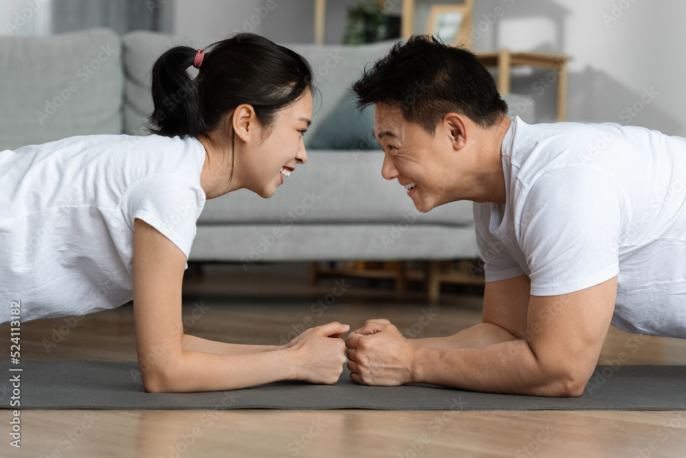 Side view of sporty asian man and woman planking together Side view of sporty asian man and woman planking together