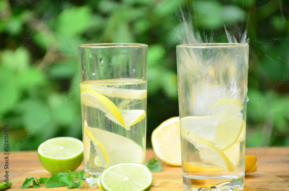 Fototapeta premium Fresh summer drink. Cold lemonade with mint lemon and lime on a nature outdoor background. Mojito summer refreshing cocktail with ice and mint