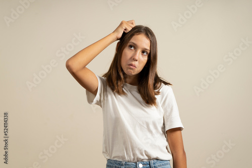 Portrait of brunette girl or young woman with puzzled, bewildered, dumb and ignorant expression on face scratching head with hand. When you don't know the answer