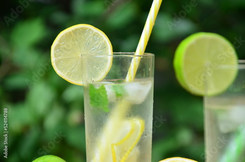 Fresh summer drink. Cold lemonade with mint lemon and lime on a nature outdoor background. Mojito summer refreshing cocktail with ice and mint