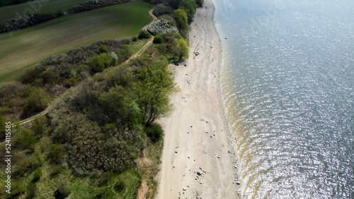 Widok z góry na plaże nad jeziorem w słoneczny dzień. 