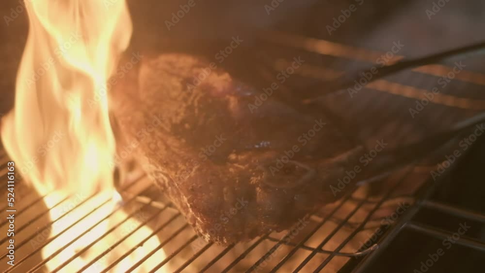 Close-up of big stake grilled on the big open fire and turned with tongs