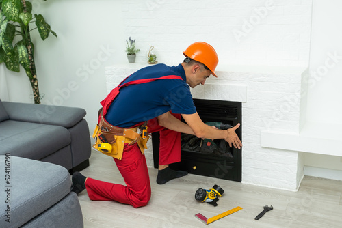 Service technician working on a fireplace inside of a residential home photo