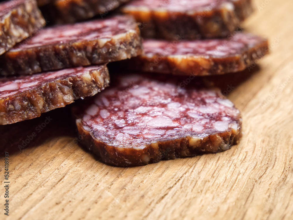 Closeup shot of sliced salami on the table. Pieces of delicious smoked sausage on a wooden cutting board.