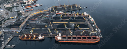 Loading coal anthracite mining in port on cargo tanker ship with crane bucket of train. Aerial top view photo