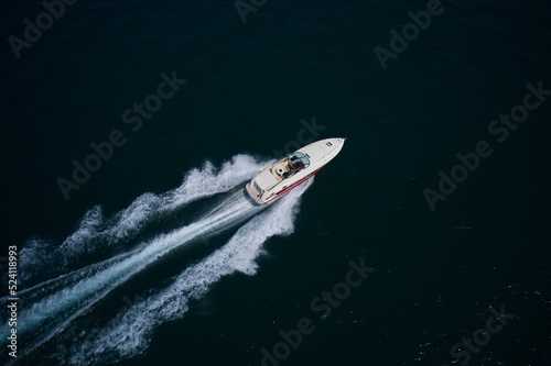 big speedboat moving fast on dark water. A large speed boat of red white color moves diagonally on the water. Super speedboat with man fast moving diagonally on the water.