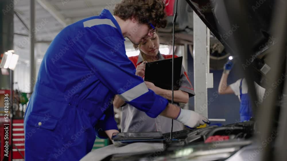 mechanic and an office worker inspecting the car in the garage.
mechanic and an office worker inspecting the car in the garage.