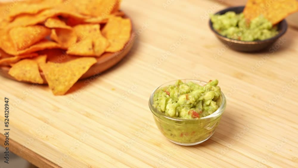 4k video, Eating Traditional Mexican food. woman hand taking cooked nachos served with Avocado and vegetables, tomato soup with cilantro. close up of cheese potato chip dip with guacamole sauce. 4k video, Eating Traditional Mexican food. woman hand taking cooked nachos served with Avocado and vegetables, tomato soup with cilantro. close up of cheese potato chip dip with guacamole sauce.