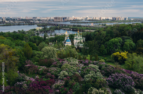 panorama beautiful top view of Kiev beautiful green park with purple flowers church near the river with a bridge on the city background on a sunny day, overall plan