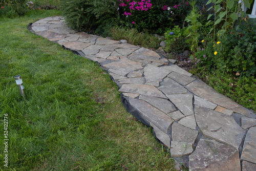 flagstone, sandstone landscaping in a country house, drainage systems and the arrangement of paths in front of the house with a lawn