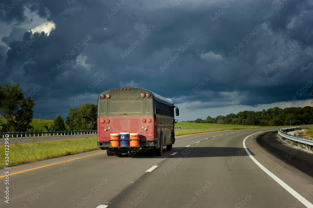 Camper Bus drive the highway towards ominous clouds.