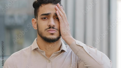 Close up portrait upset looser sad frustrated disappointed failure Arabian Hispanic Indian businessman face palm reaction stress with problem bearded man lost trouble unpleasant worry outdoors in city
