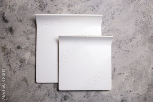 white ceramic square plates on a concrete background