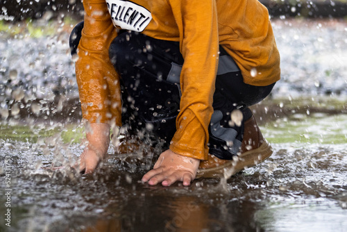 Young boy jumping in a mud puddle